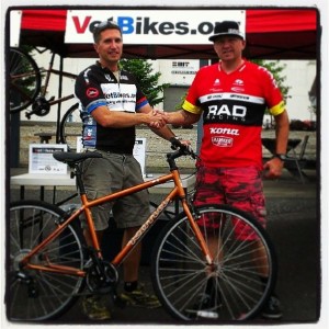 Alex Young accepts a donated bike from Jim Brown and the Kona Bikes.